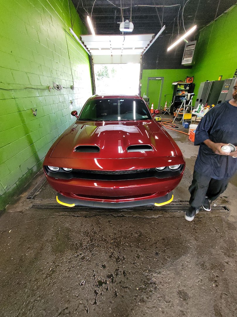 Red Dodge Challenger freshly detailed inside the green-walled wash bay